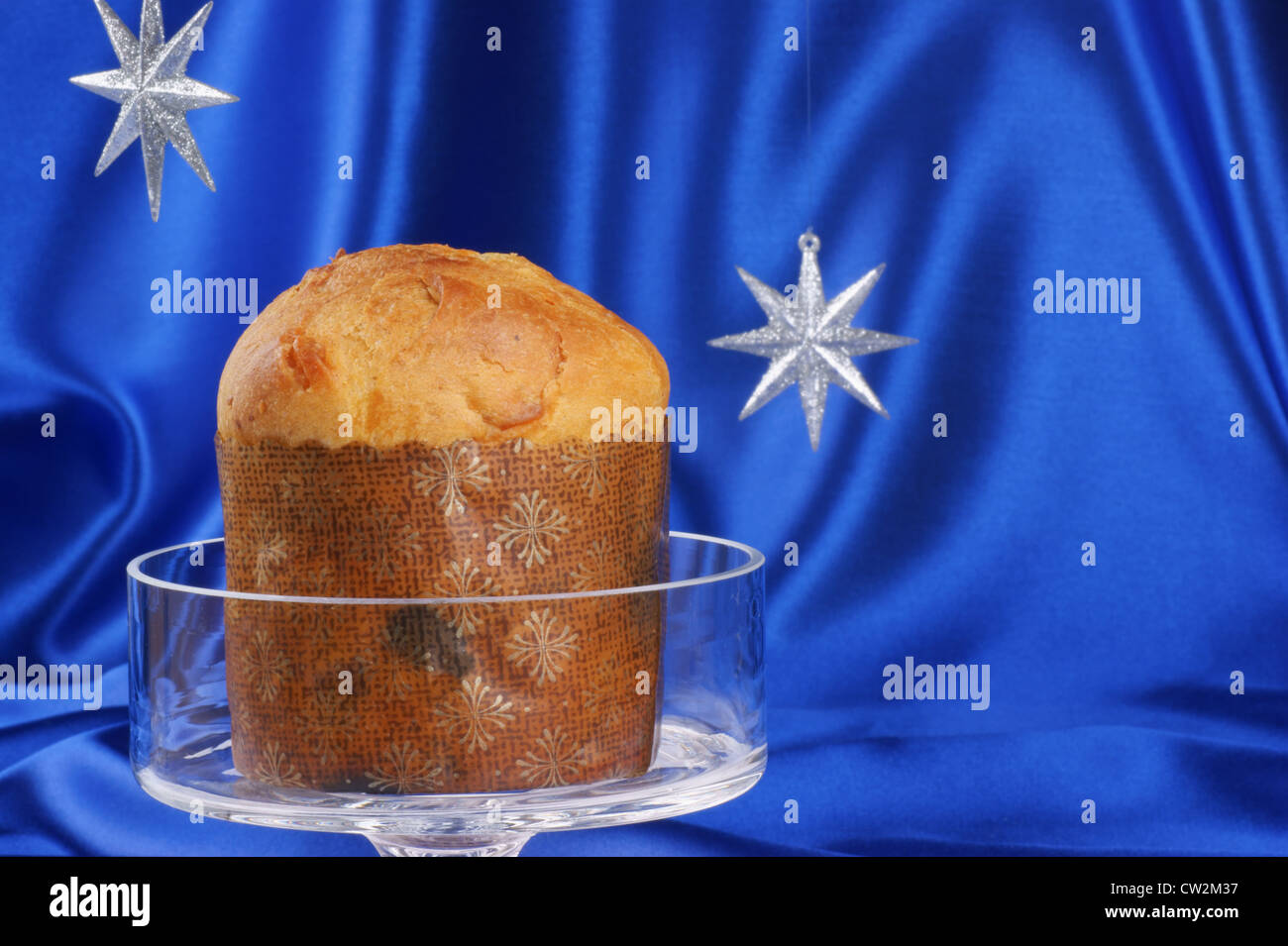 Composizione di natale su un brillante sfondo blu. Il Panettone, un tipico italiano torta di Natale, servita su una torta di vetro stand. Foto Stock