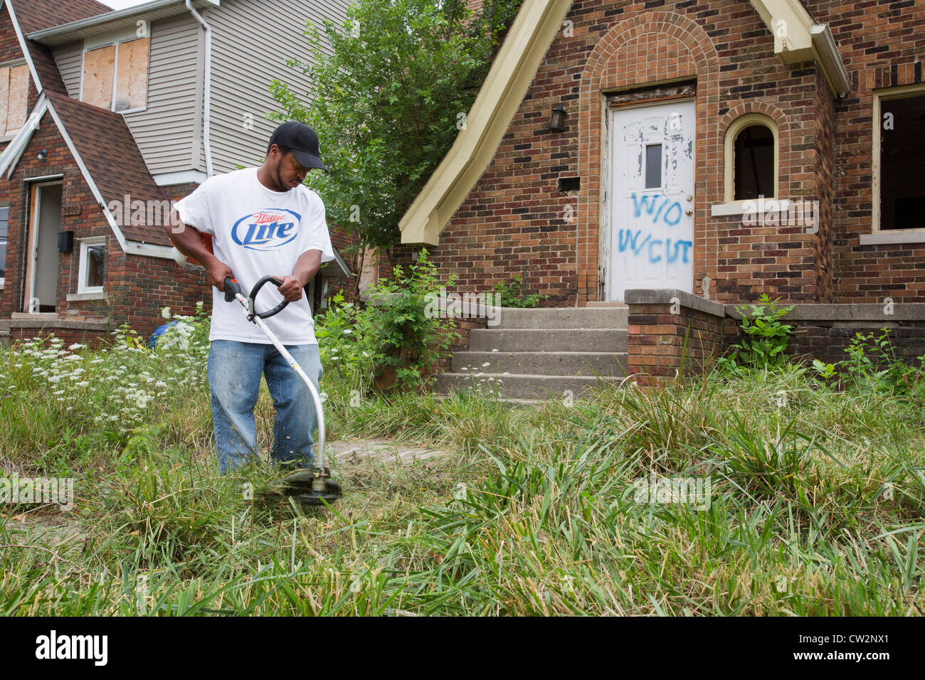 Detroit, Michigan - i membri delle tre miglia di blocco Club tagliare erbe infestanti e rimuovere illegalmente nel cestino di dumping in una casa abbandonata. Foto Stock