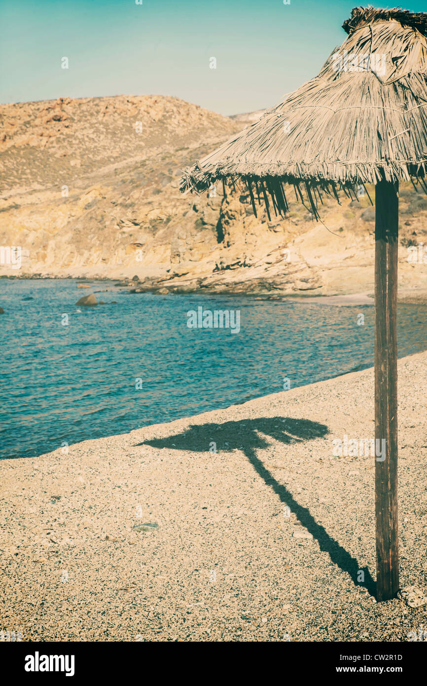 Rafia ombrellone su una spiaggia deserta Foto stock - Alamy