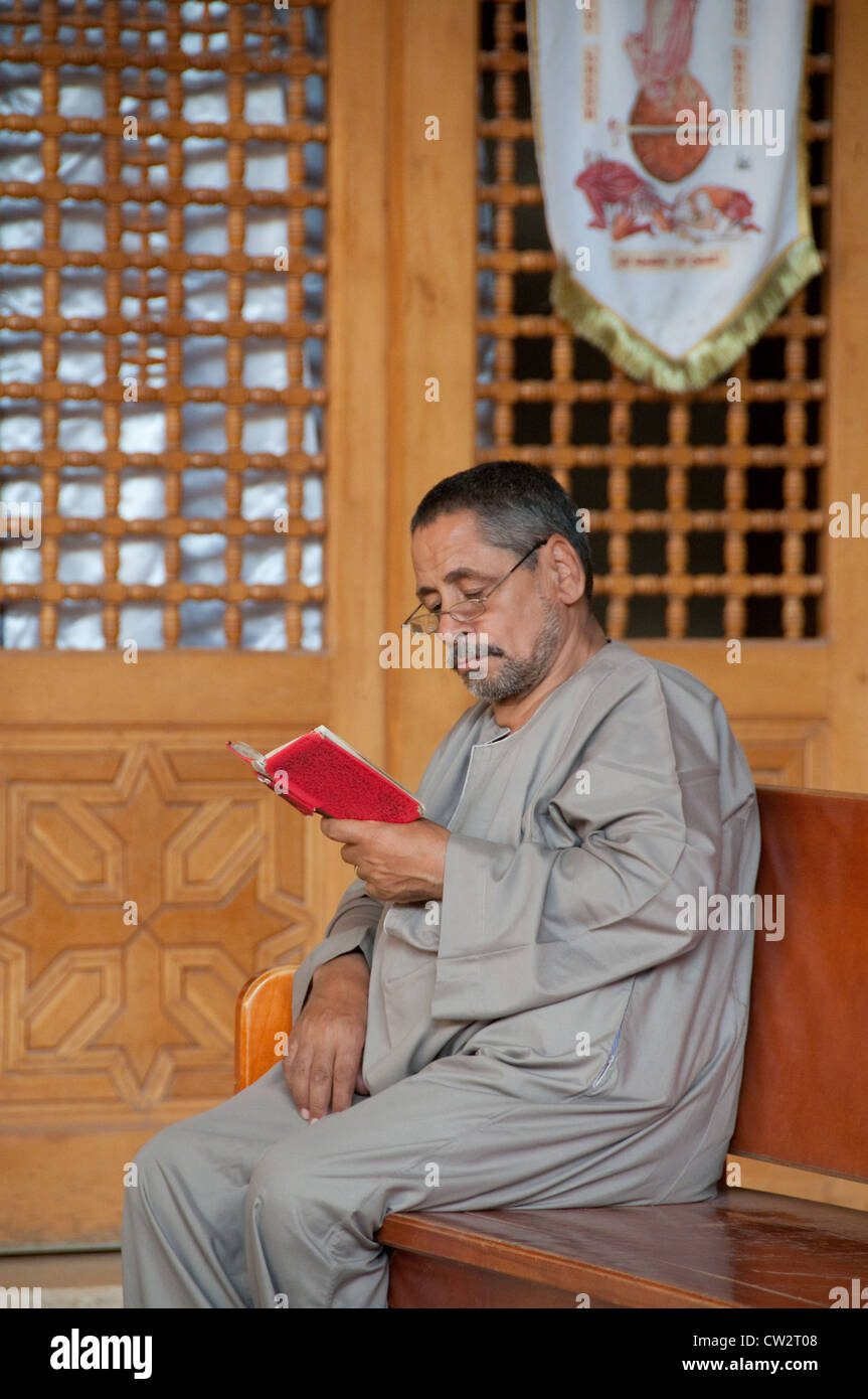 Uomo di pregare con la Bibbia in una chiesa situata nel monastero di Le colline Muqattam Cairo Egitto Foto Stock