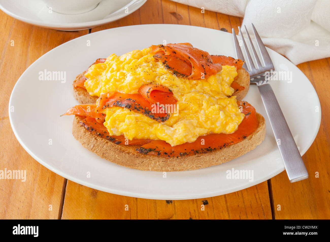 Condite il salmone affumicato con uova strapazzate su pane tostato. Foto Stock