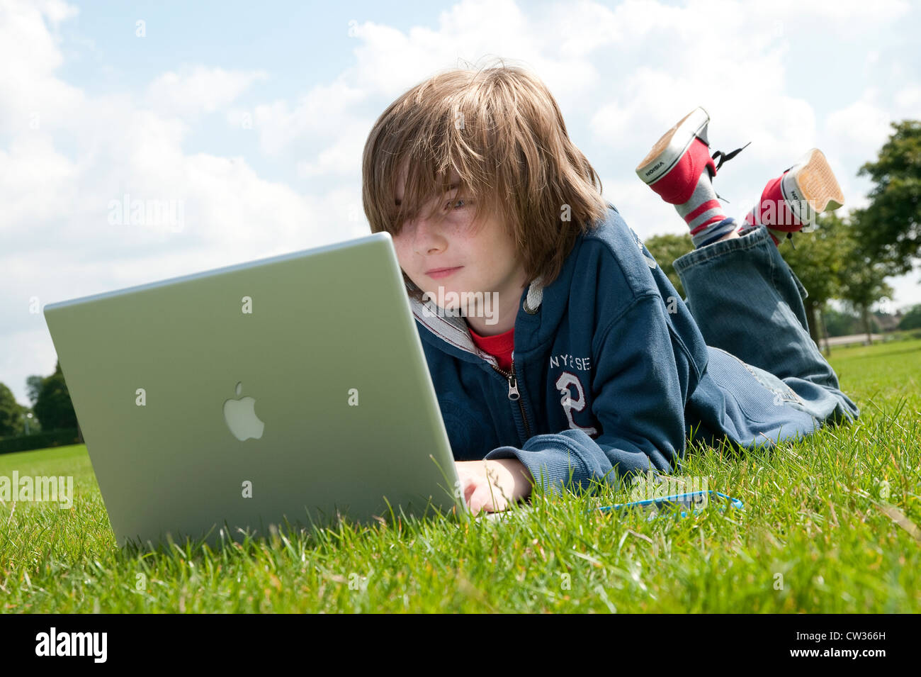 Giovane maschio boy utilizzando il computer portatile nel parco urbano Foto Stock