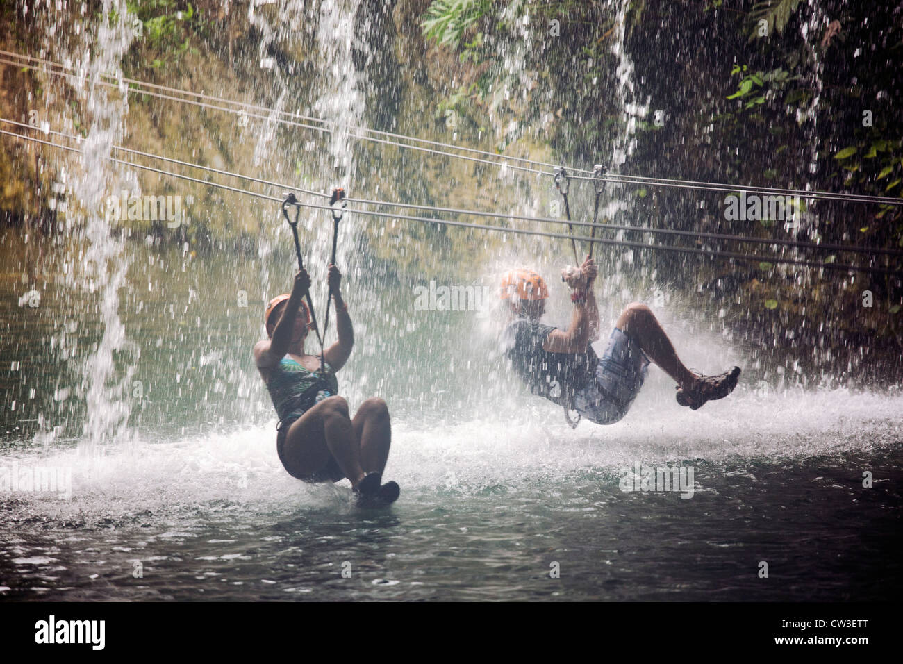 Due persone fodera zip attraverso una cascata di Xplor, una naturale parco avventura situato nella Riviera Maya, Foto Stock