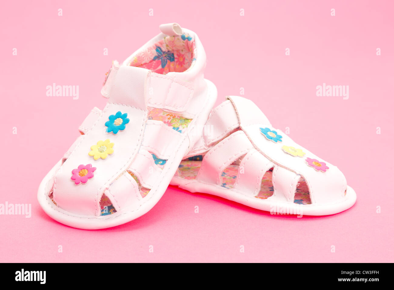 Una coppia di ragazze baby scarpe o sandali - studio shot su una pianura sfondo rosa Foto Stock