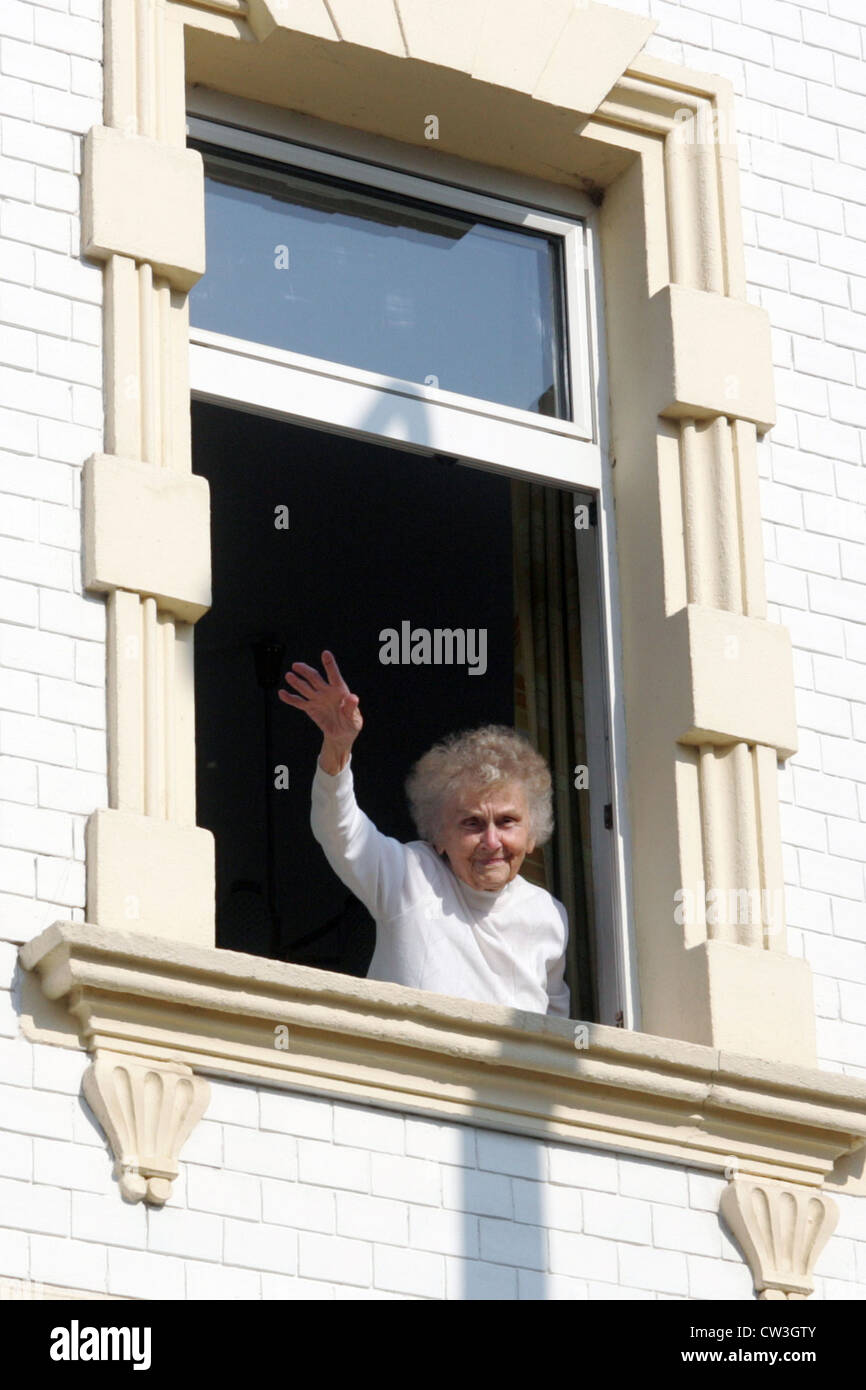 Berlino, una vecchia donna sventolando da una finestra del suo appartamento Foto Stock