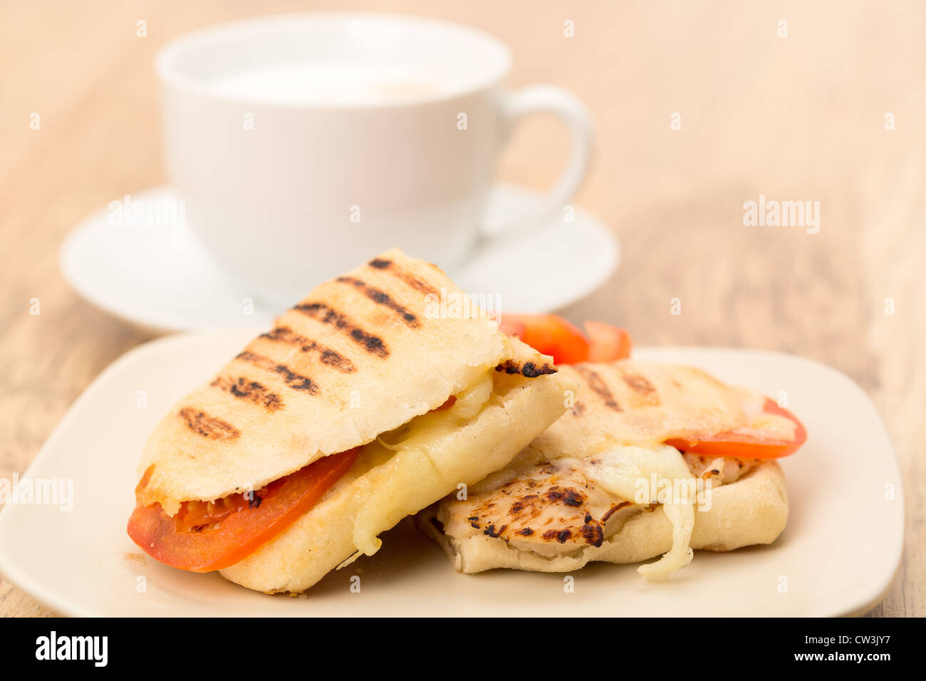 Pollo tostato, pomodoro e mozzarella Panini sandwich che è stato tagliato a metà e posto su una piastra Foto Stock