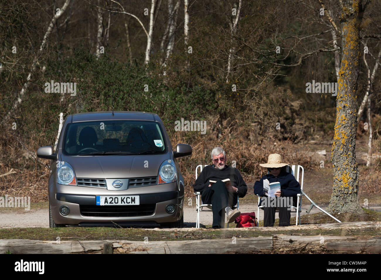 Due persone di mezza età persone in sedie da picnic accanto a AUTO lettura nel sole. Foto Stock