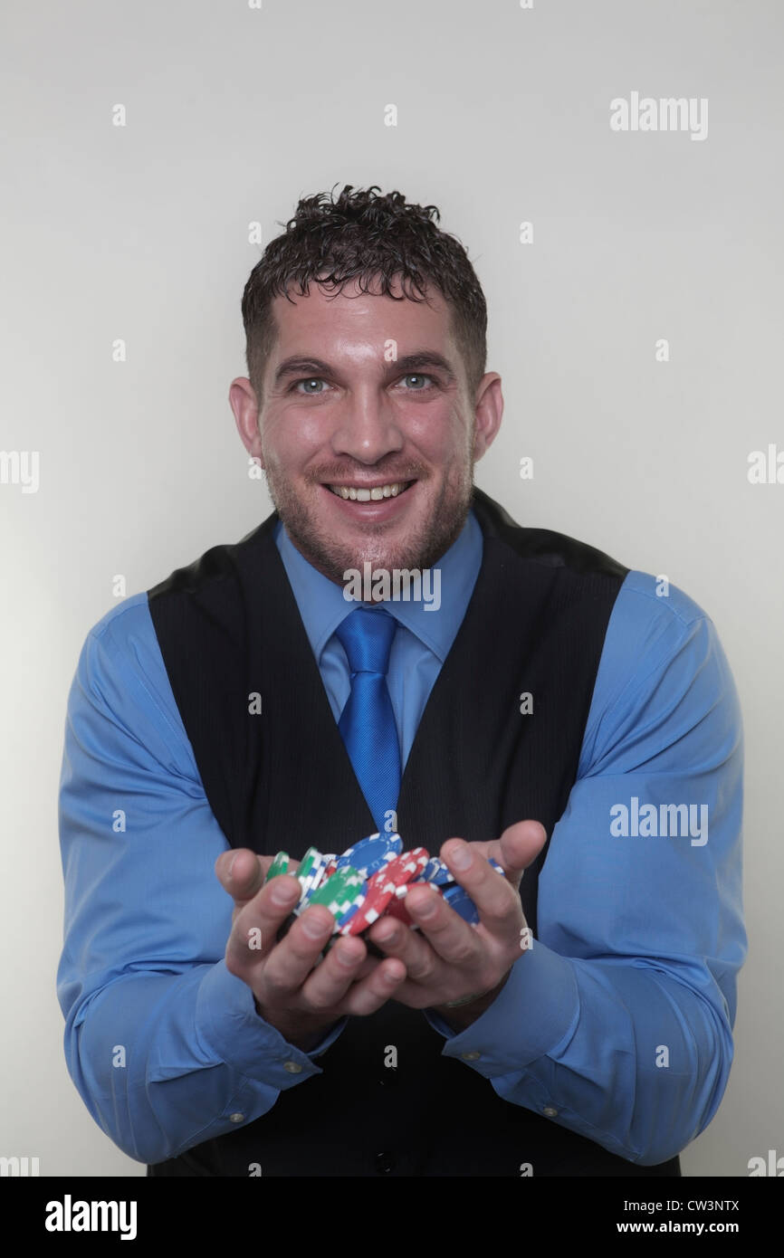 Bel uomo in possesso di una partita di poker chips in due mani cercando molto felice Foto Stock