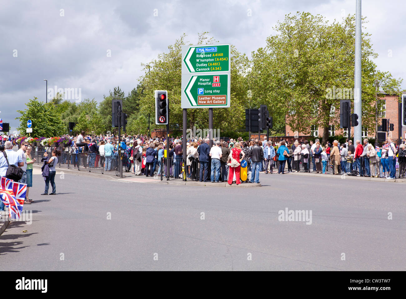 Linea di folle le strade di Walsall, West Midlands per attendere il passaggio della torcia Olimpica e il suo portatore Foto Stock