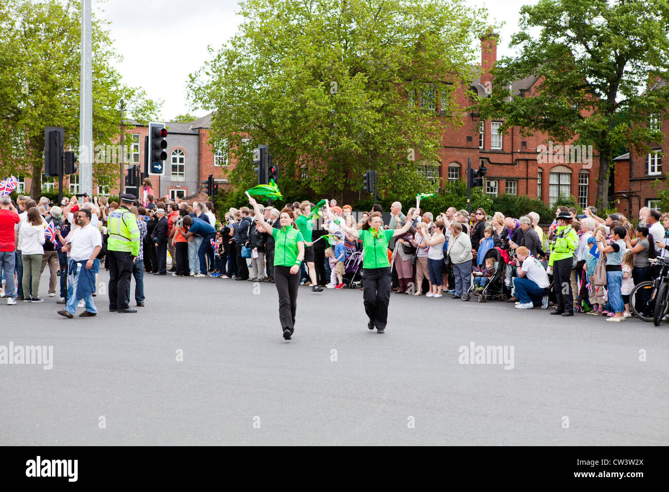 La folla lungo le strade di Walsall, West Midlands per attendere il passaggio della torcia Olimpica e il suo portatore preceduto da sponsor Foto Stock