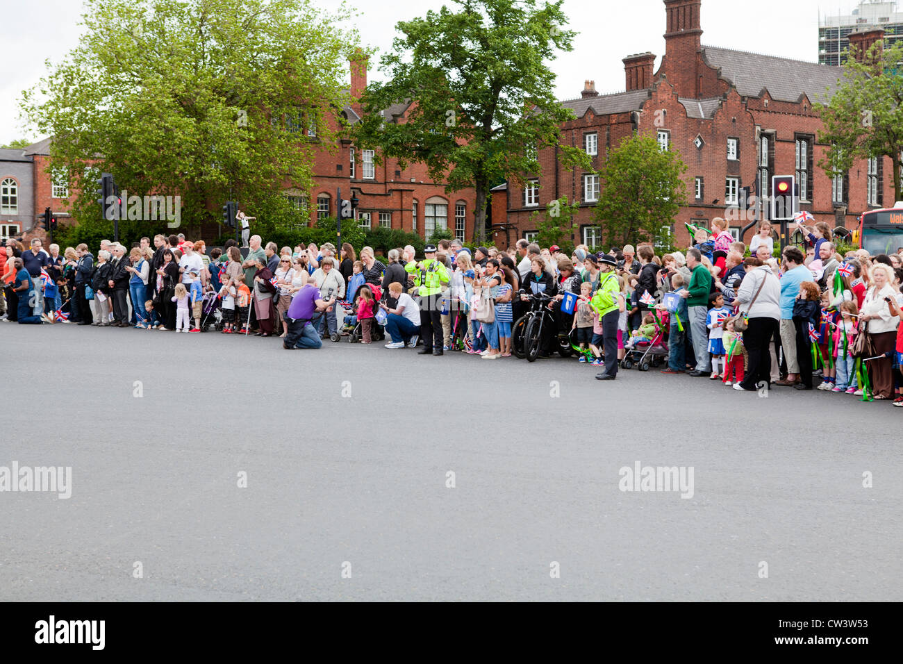 Linea di folle le strade di Walsall, West Midlands per attendere il passaggio della torcia Olimpica e il suo portatore Foto Stock
