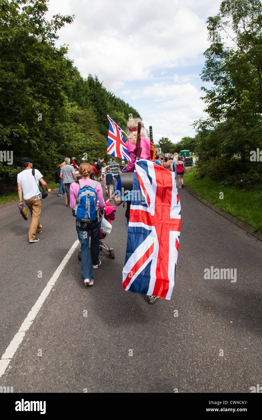 Una famiglia drappeggiati in una unione bandiera a casa a piedi dopo aver guardato la Olympic escursioni in bicicletta da corsa su strada a Londra 2012. Foto Stock