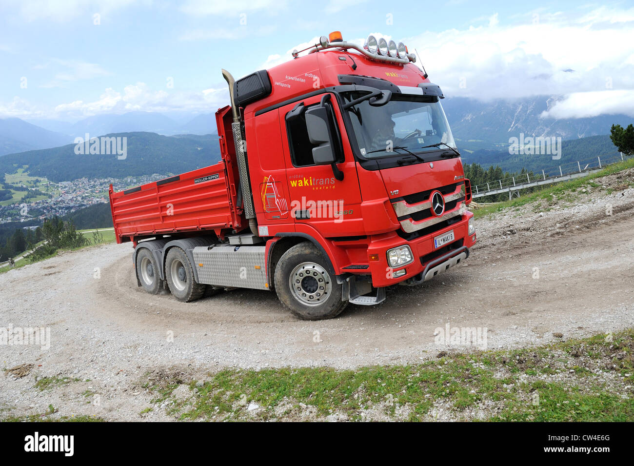 Mercedes actros quattro ruote di azionamento carrello ribaltabile guida su una montagna ghiaiose via per fornire materiale per una stazione di sci. Foto Stock