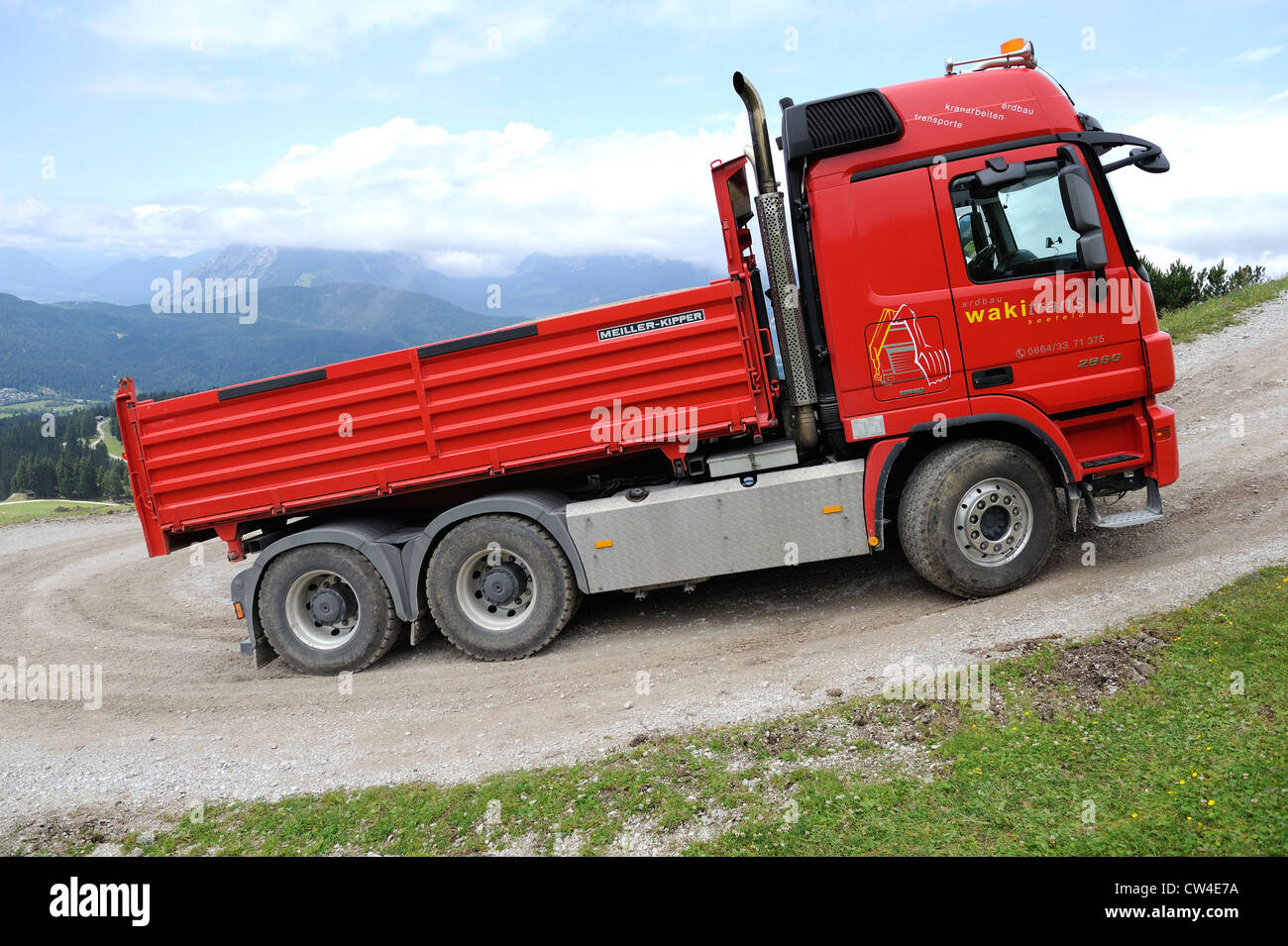 Mercedes actros quattro ruote di azionamento carrello ribaltabile guida su una montagna ghiaiose via per fornire materiale per una stazione di sci. Foto Stock