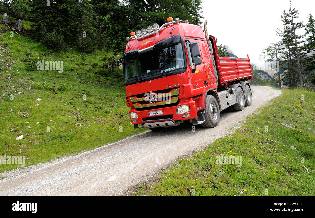 Mercedes actros quattro ruote di azionamento carrello ribaltabile guida su una montagna ghiaiose via per fornire materiale per una stazione di sci. Foto Stock