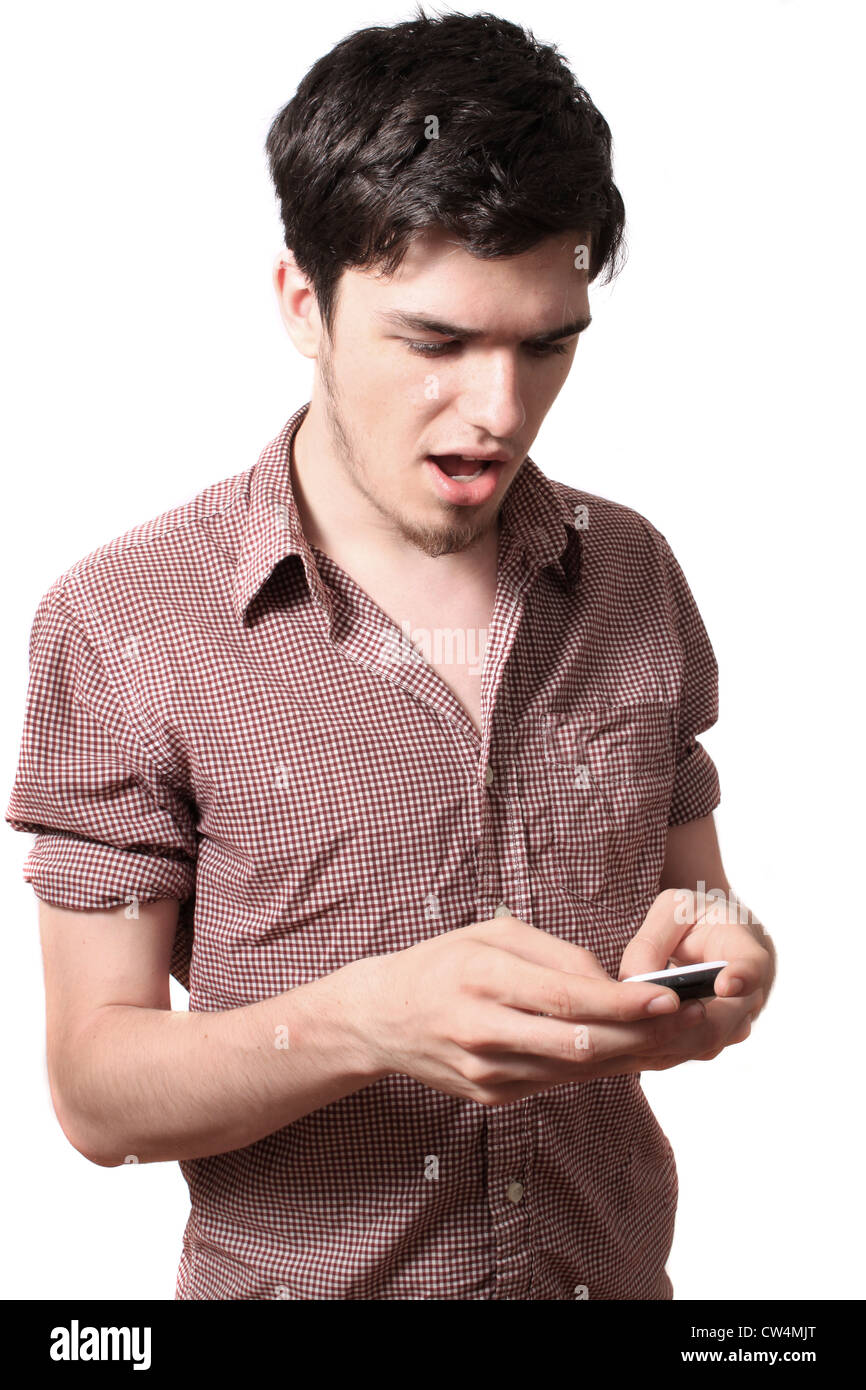 Diciottenne giovane azienda il suo cellulare su sfondo bianco con sorpresa o attonito sguardo sul suo viso Foto Stock