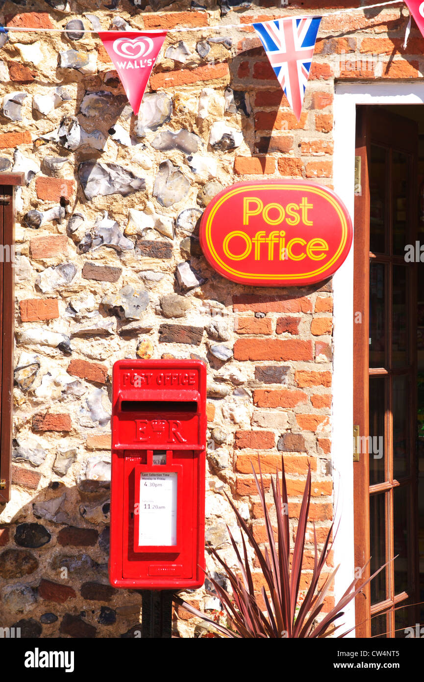 Royal Mail red casella di posta al di sotto di un ufficio postale firmare in un piccolo villaggio di Norfolk Foto Stock
