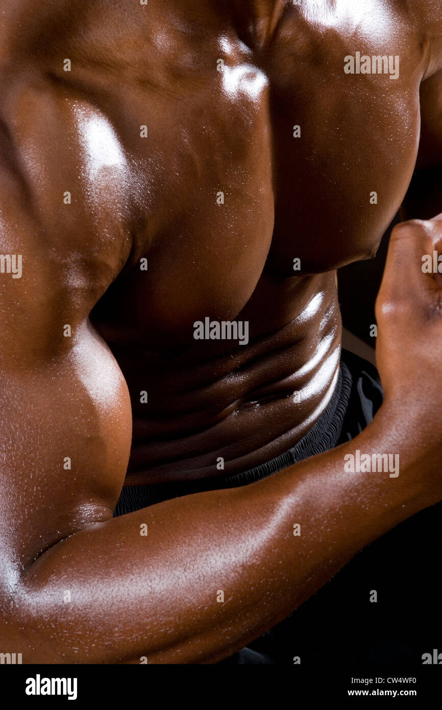Sezione mediana di un giovane uomo di flettere i muscoli in palestra Foto Stock