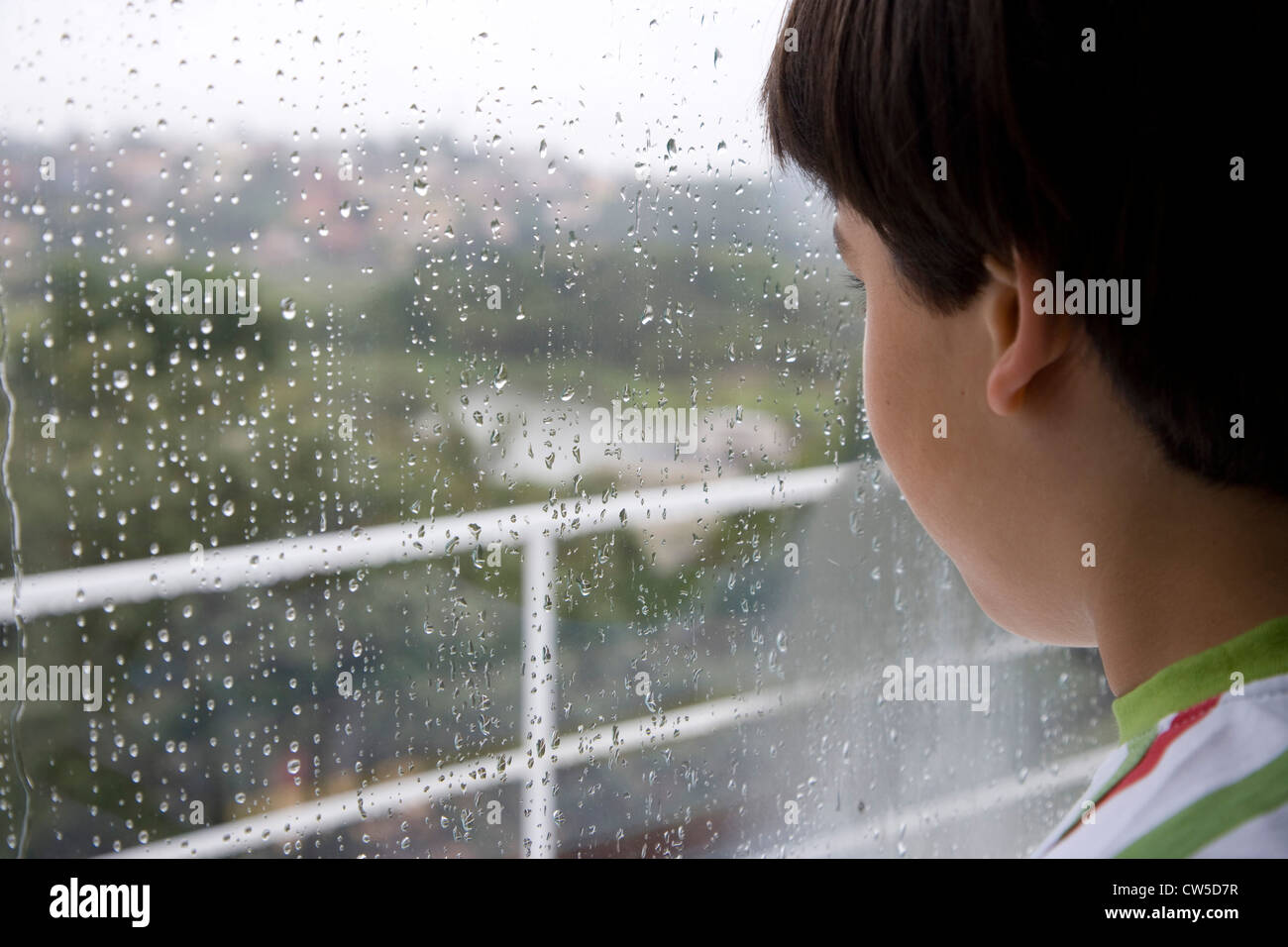 Close-up di un ragazzo che guarda fuori della finestra in un giorno di pioggia Foto Stock