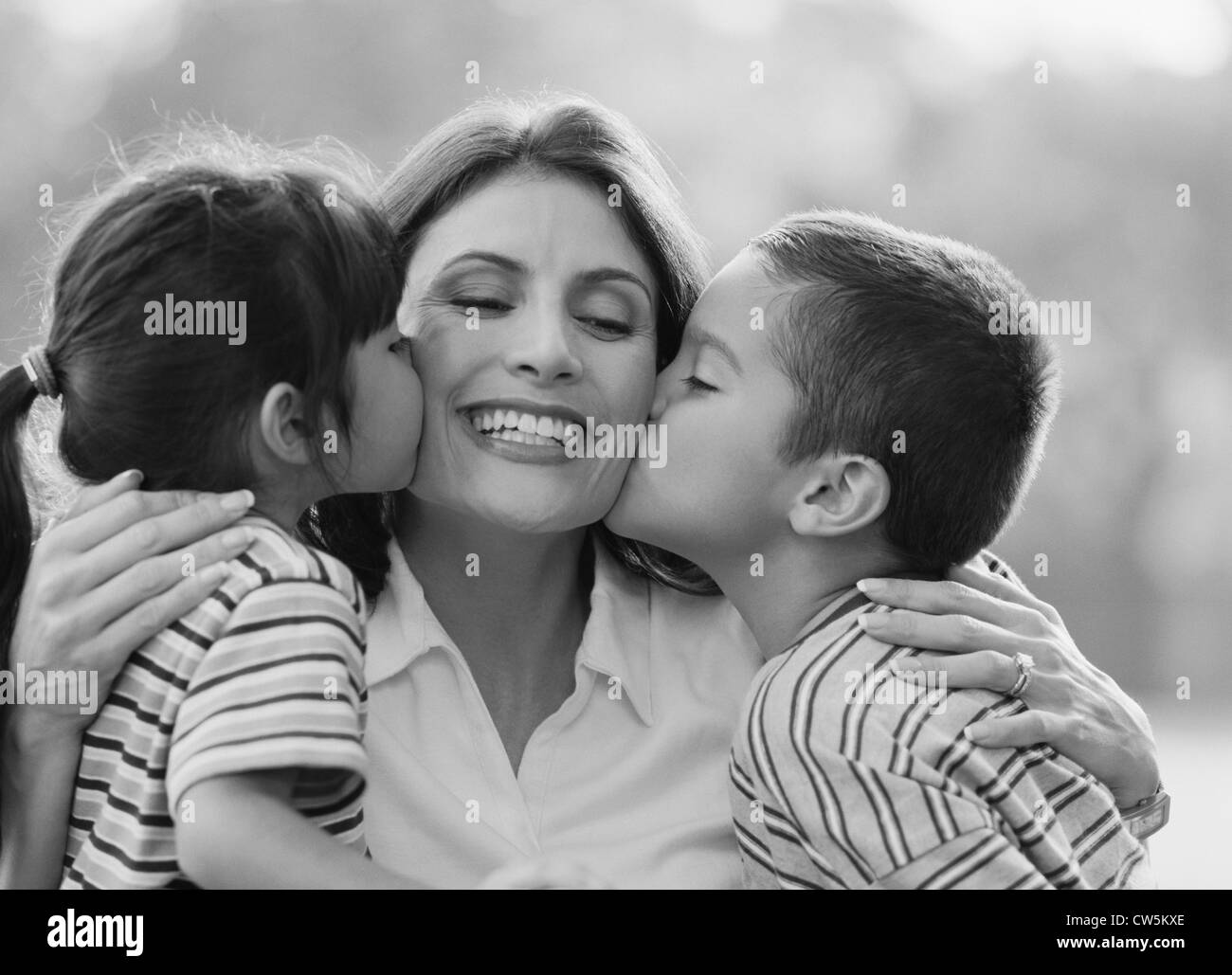 Due bambini baciare la loro madre Foto Stock