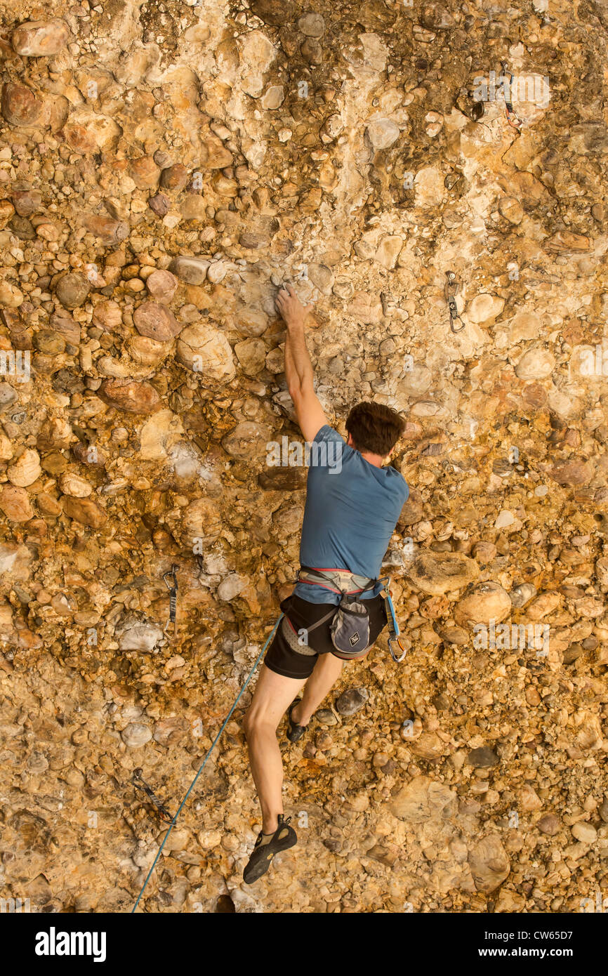 L'uomo in alto su una parete di roccia di tentare di manovra attorno a una sporgenza. Orario estivo in Utah montagne, soleggiato e caldo. Foto Stock