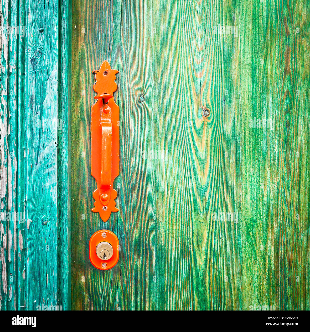 Arancione brillante maniglia della porta su un verde porta di legno Foto Stock