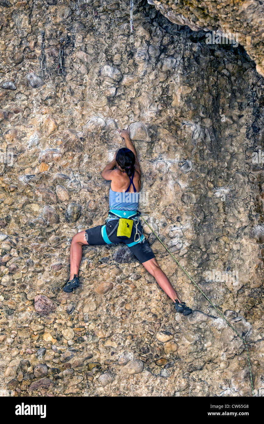 Donna in alto su una parete di roccia di tentare di manovra attorno a una sporgenza. Orario estivo in Utah montagne, soleggiato e caldo. Foto Stock