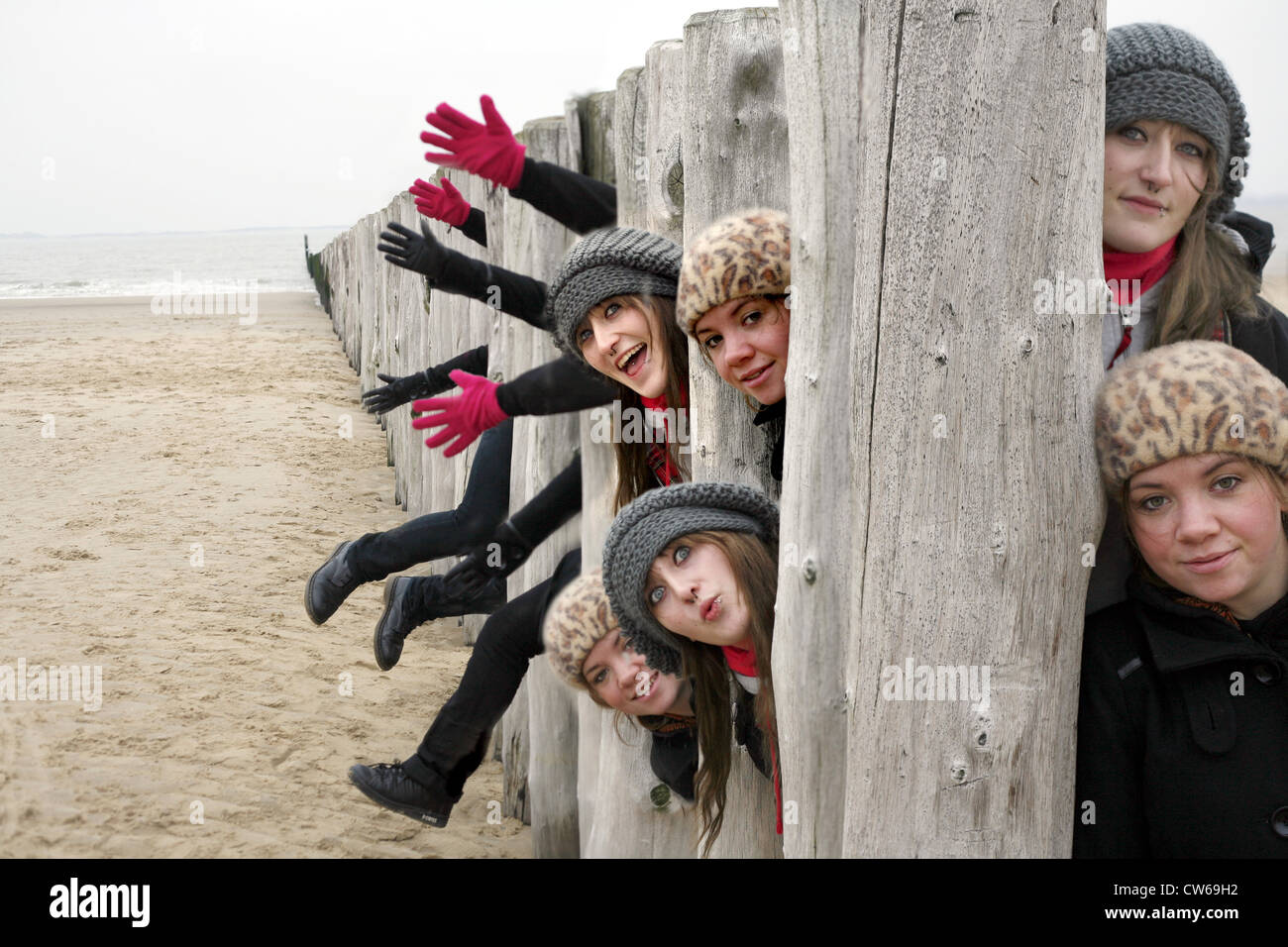 Due giovani donne cercando tra i pali di legno di groyne, Paesi Bassi Zeeland, Breskens, Sluis Foto Stock