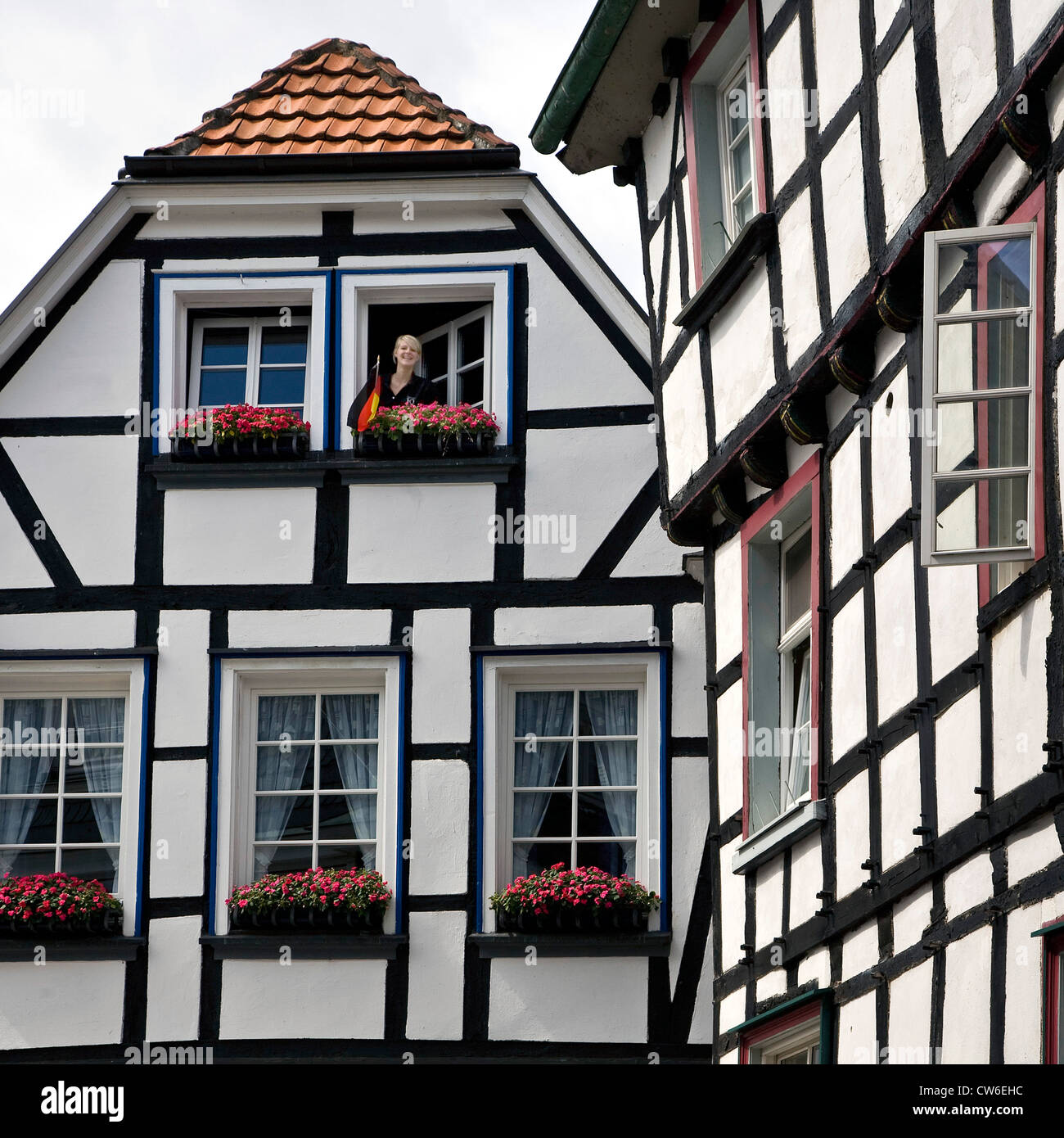 Giovane donna che guarda fuori da una finestra della casa con travi di legno nella storica città vecchia di Hattingen, in Germania, in Renania settentrionale-Vestfalia, la zona della Ruhr, Hattingen Foto Stock