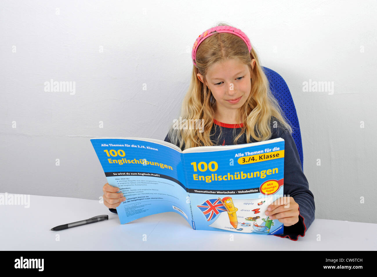 Schoolgirl lettura felicemente in un libro in inglese Foto Stock