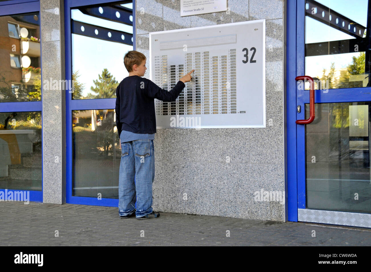 9 anni vecchio ragazzo in corrispondenza di una piastra porta di un edificio a più piani in Chorweiler, in Germania, in Renania settentrionale-Vestfalia, Colonia Foto Stock