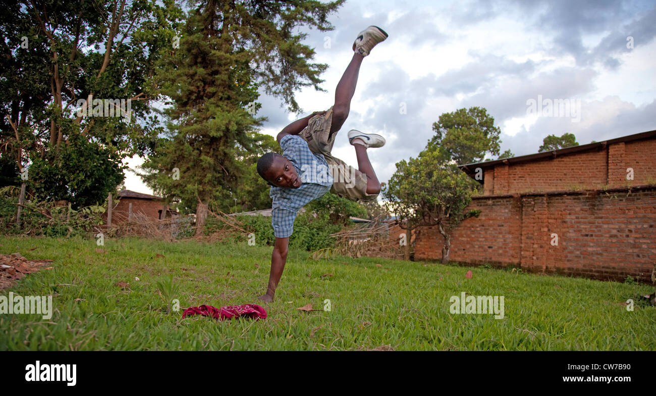 Ragazzo adolescente che mostra un breakdance figura su un prato facendo un handstand su un braccio, Burundi, Makamba, Makamba Foto Stock