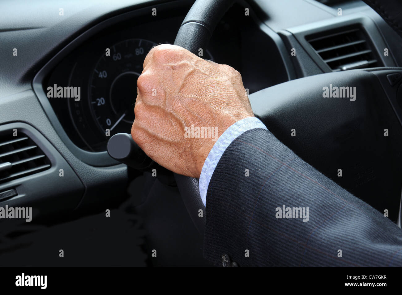 Primo piano di una mano di un uomo mantiene il volante della sua vettura. Formato orizzontale. Auto e autista sono irriconoscibile. Foto Stock