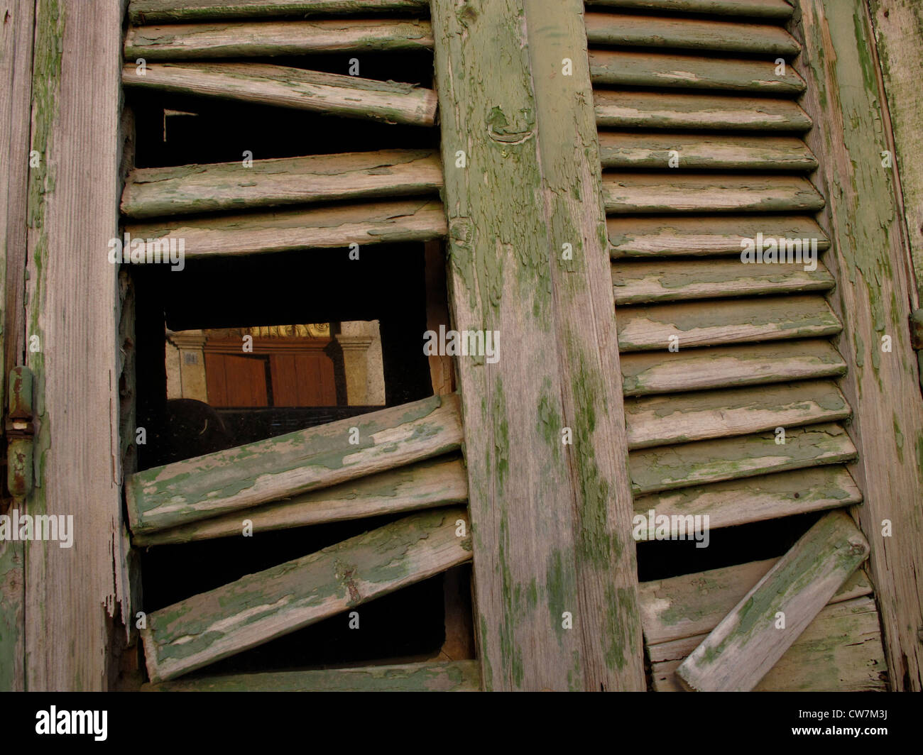 La rottura di una finestra verde otturatore da una vecchia casa in Mediterraneo Cipro, segni della guerra e della povertà nella regione Foto Stock