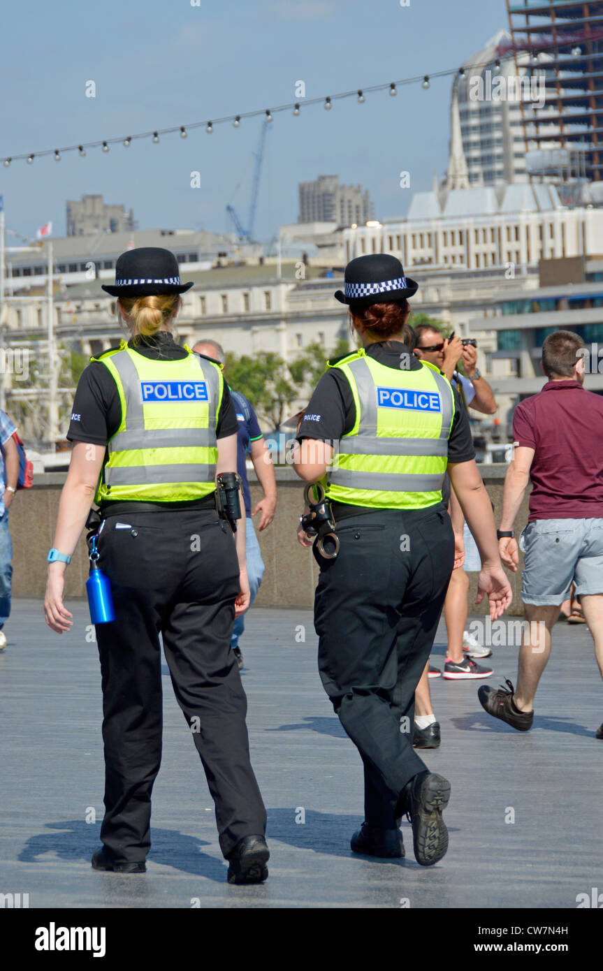 Vista posteriore di due poliziotti metropolitane del WPC in uniforme in pattuglia a piedi sul Tamigi presso Butlers Wharf Southwark Londra Inghilterra Regno Unito Foto Stock