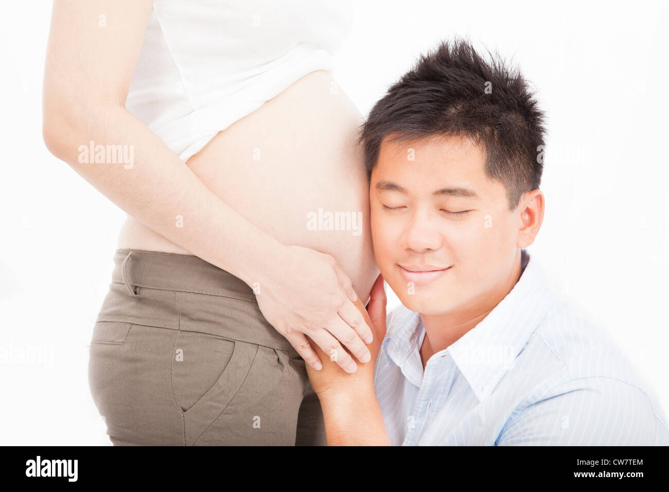 Asian Padre ascoltando la sua moglie incinta la pancia Foto Stock