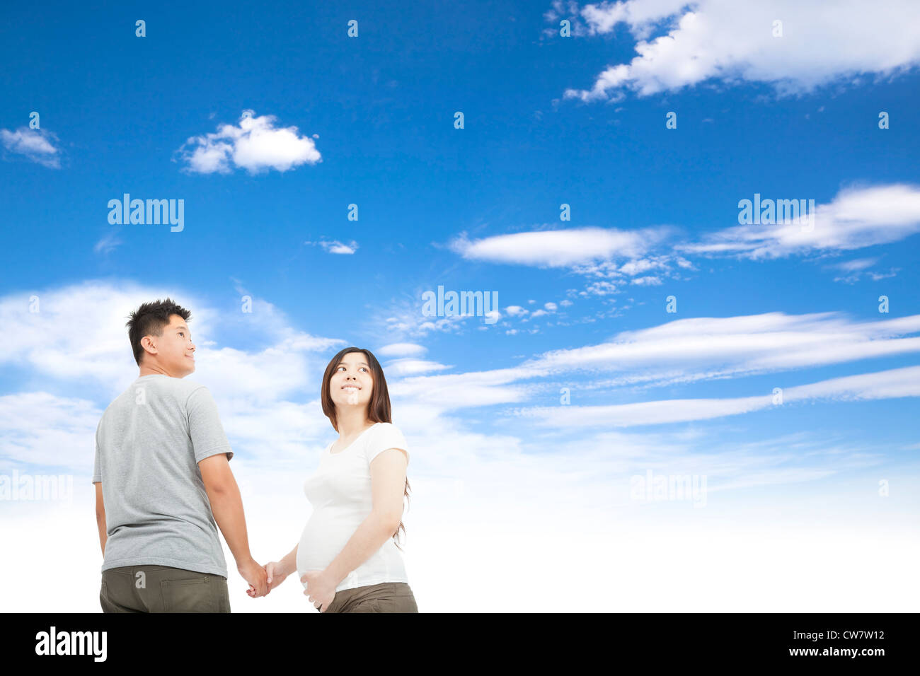 Il marito tenendo moglie incinta la mano e Sfondo nuvola Foto Stock