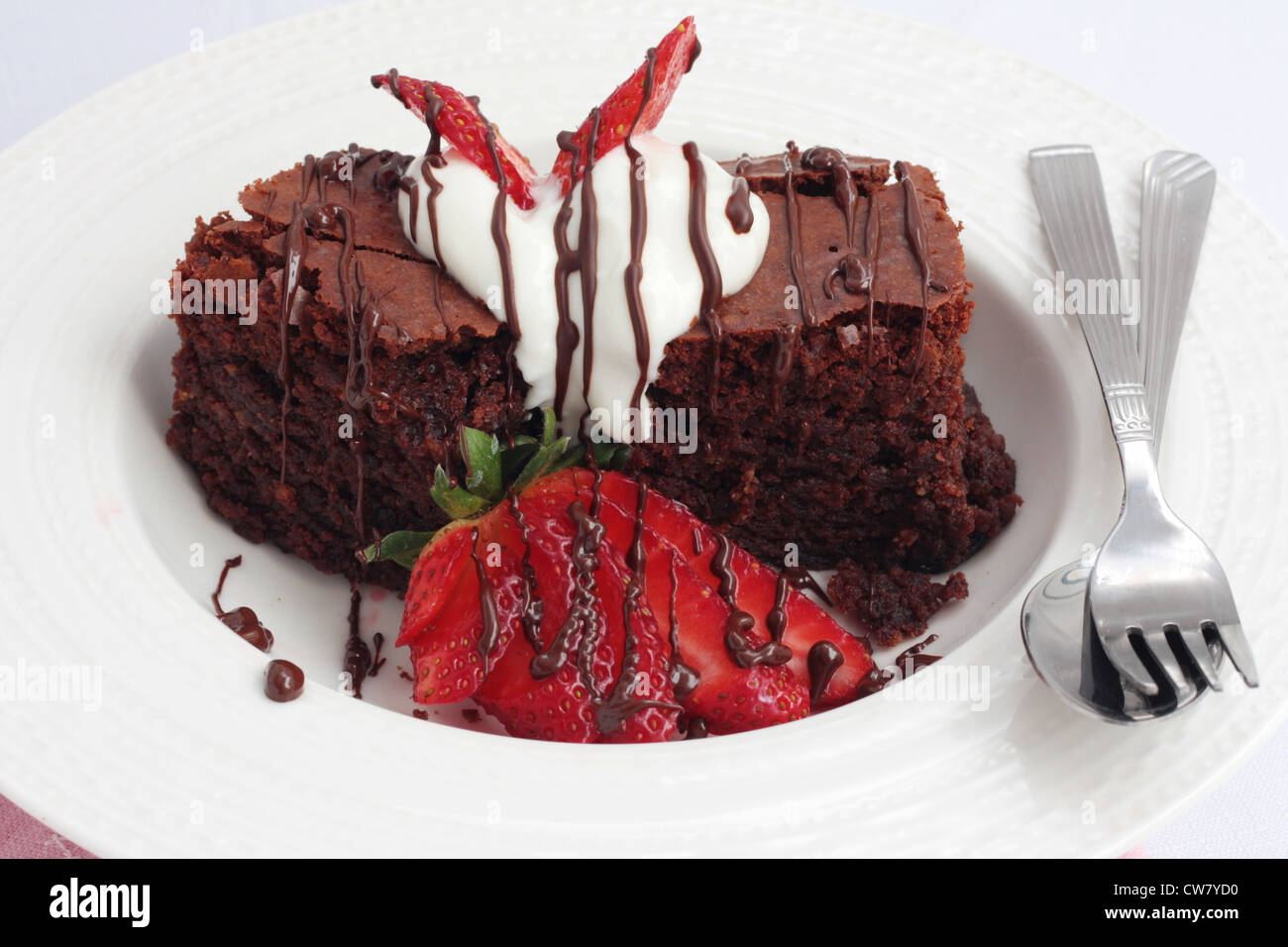 Un piatto di brownie al cioccolato con panna e fragole. Foto Stock