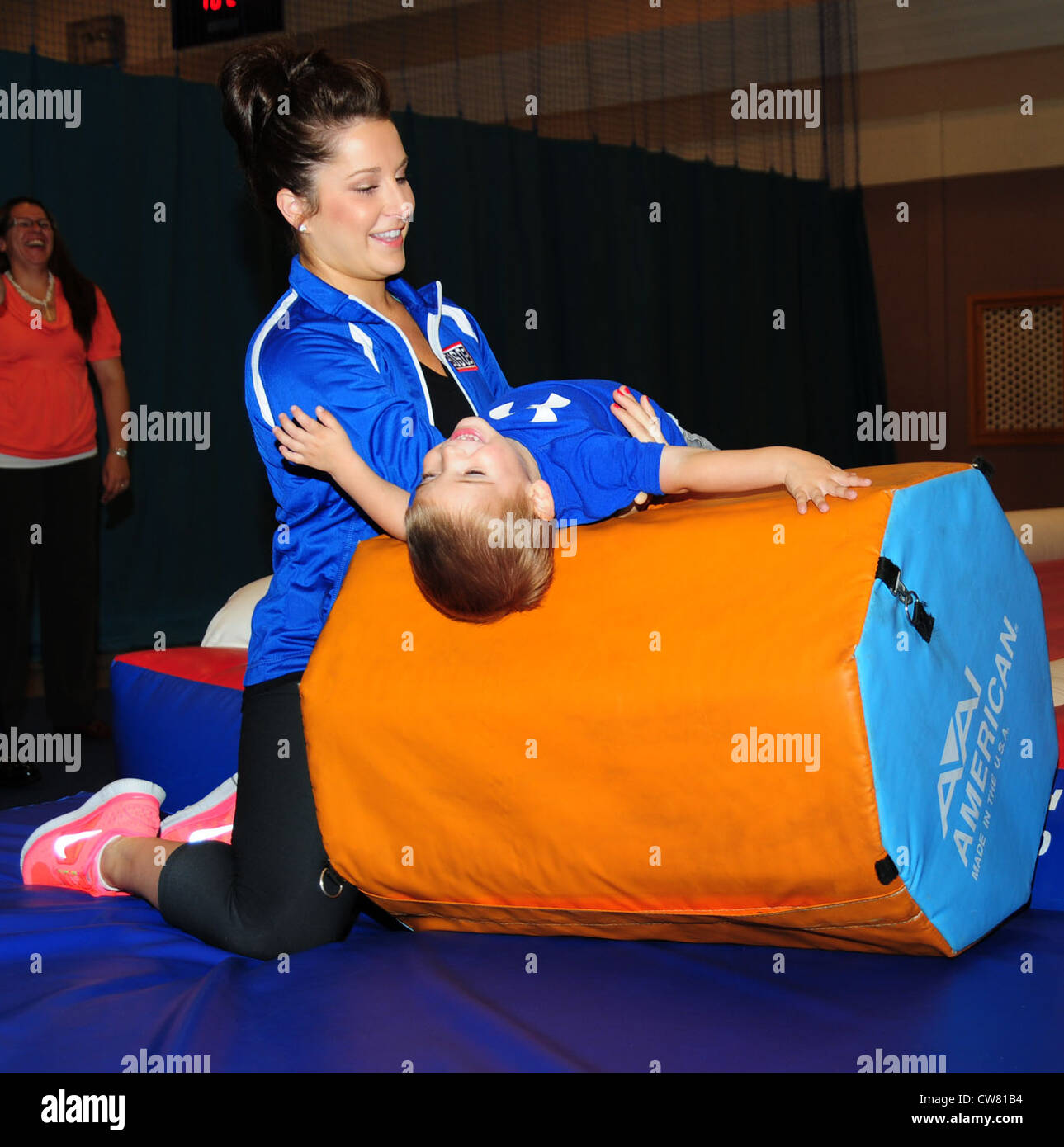 Carly Patterson, ginnasta olimpionica e medaglia d'oro, aiuta Christian graham, 2, pratica un rotolo indietro durante una toddlersâ€™ di classe di ginnastica aug. 13, 2012, presso la raf mildenhall centro giovanile. Patterson era 16 quando ha vinto la sua medaglia d'oro ad Atene, Grecia, nel 2004. ha visitato la base come parte di un regno servizi tour dell'organizzazione. Foto Stock