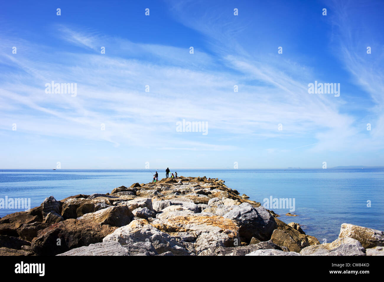 Buon nuvole nel cielo sopra di calme acque del mar mediterraneo con molo roccioso a costa del sol a marbella, Spagna. Foto Stock