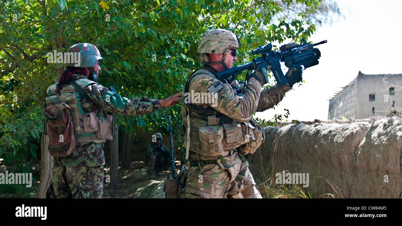 Un soldato dell'esercito nazionale afgano si alza per aiutare a far notare Sgt. Cody Outcalt, un soldato con il 2 ° Platoon, Apache Company, 1 ° Battaglione, 23 ° Reggimento Fanteria, dove sparare il suo M320 durante un fuoco con gli insorti nel sud dell'Afghanistan, 30 luglio 2012. Foto Stock