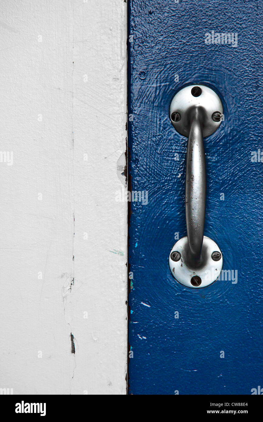 Acciaio inox maniglia fissata con 6 viti su una porta blu su una metà destra sull'immagine.Nell'altra metà un di legno bianco Foto Stock