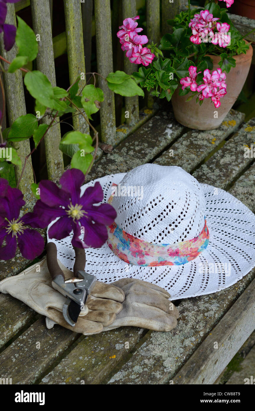 Sedia da giardino con signore cappello per il sole e secateurs Foto Stock