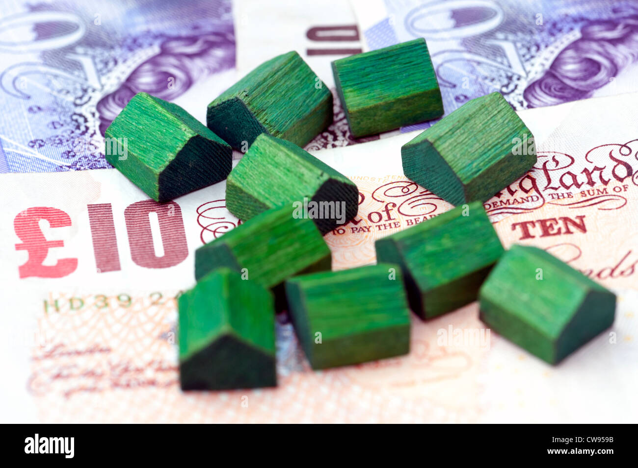 Case giocattolo seduto sul pound note che rappresentano la casa prezzi o servizi finanziari connessi con il mercato degli alloggi. Foto Stock