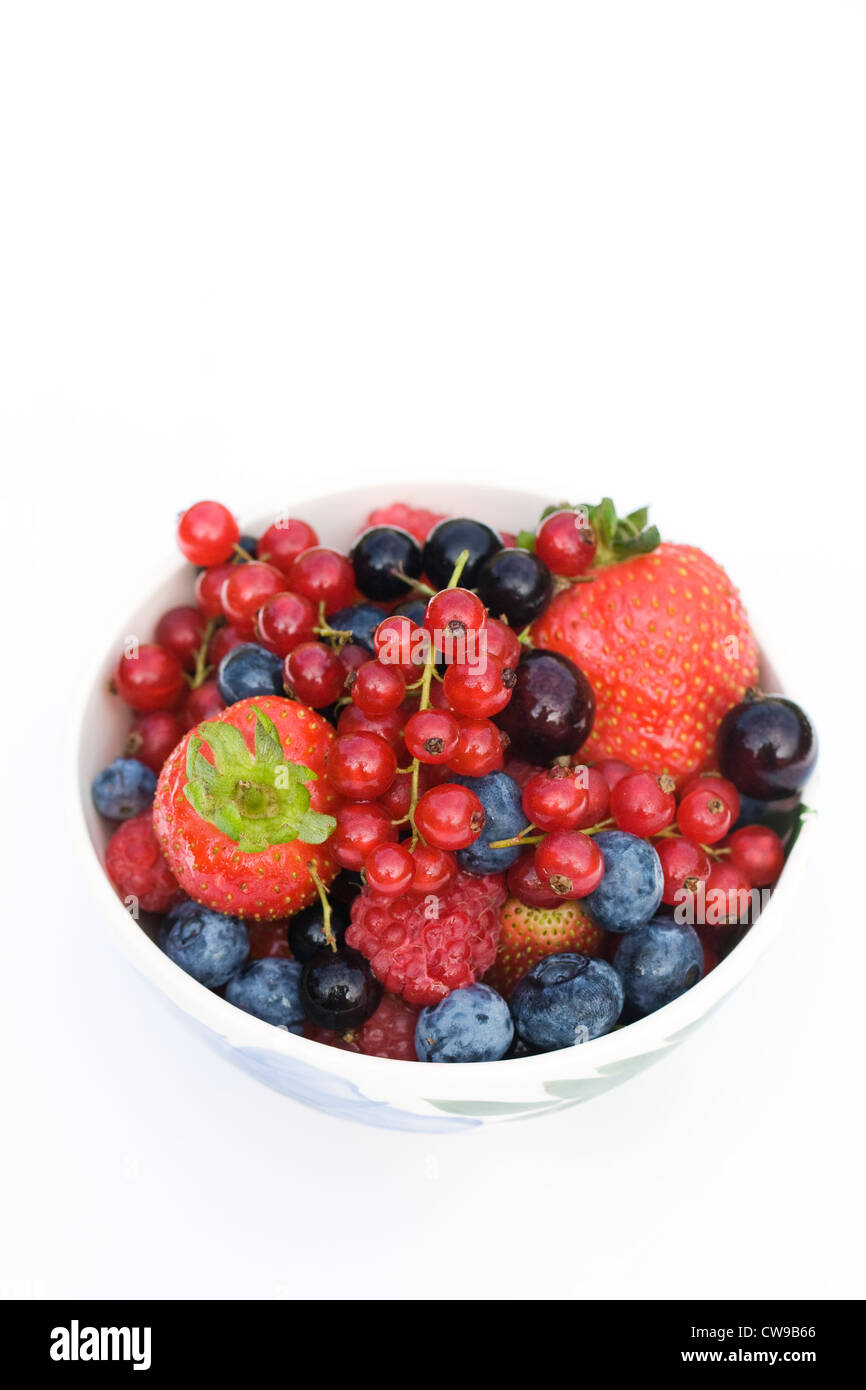 Una ciotola di colorati misti di frutti di bosco estivi contro uno sfondo bianco. Foto Stock