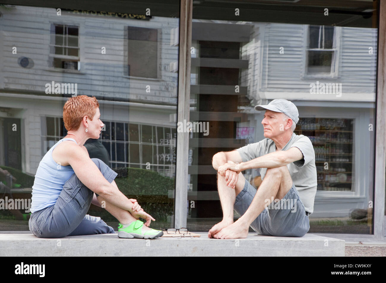Donna e uomo che parla mentre è seduto su una panchina all'esterno. Foto Stock