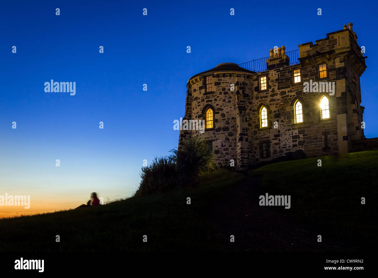 Silhouette di una persona seduta vicino alla casa gotica in Edinburgh Foto Stock