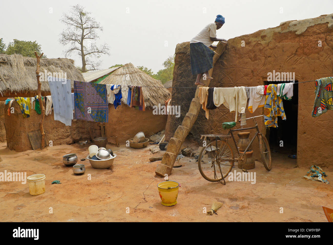 Donna su scala log in famiglia composto, Mognori Eco-Village, Ghana Foto Stock