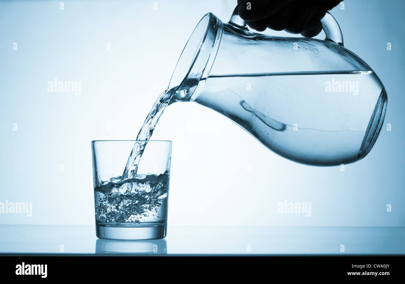 Versare acqua da una brocca in un bicchiere Foto Stock