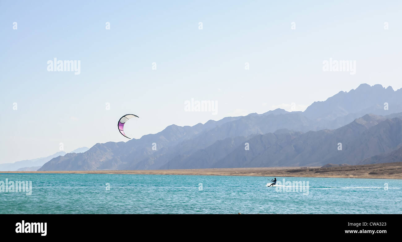 Il kite-surfer in laguna circondata da montagne del deserto Foto Stock